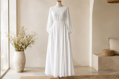 Robe longue blanche à manches longues, col rond, taille élastique et poches latérales sur mannequin sans tête.